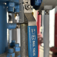 Close-up of an industrial pipe valve with a blue handle.